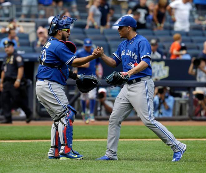Toronto Blue Jays relief pitcher Roberto Osuna, right, celebrates with catcher Dioner Navarro after the ninth inning of the baseball game against the New York Yankees at Yankee Stadium, Sunday, Aug. 9, 2015 in New York. The Blue Jays defeated the Yankees 2-0. (AP Photo/Seth Wenig)