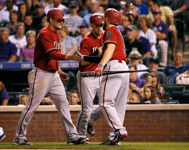 Arizona Diamondbacks' Ender Inciarte (5) greets Phil Gosselin and Chris Owings after scoring on a Aaron Hill two run double during the seventh inning of the second game of a baseball doubleheader Tuesday, Sept. 1, 2015, in Denver. (AP Photo/Jack Dempsey)